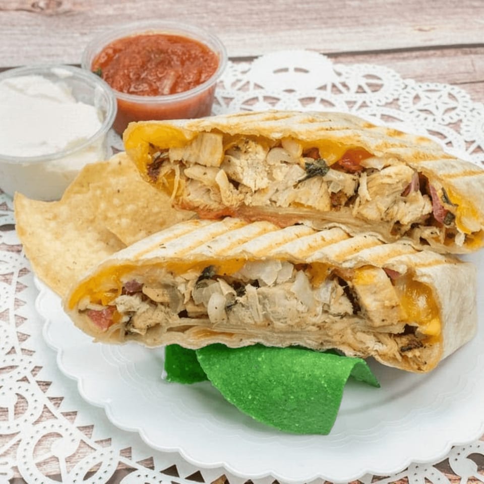 Grilled chicken quesadilla halves with melted cheese, served with tortilla chips, salsa, and sour cream.